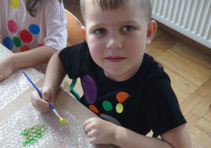Chłopiec maluje na folii bąbelkowej
